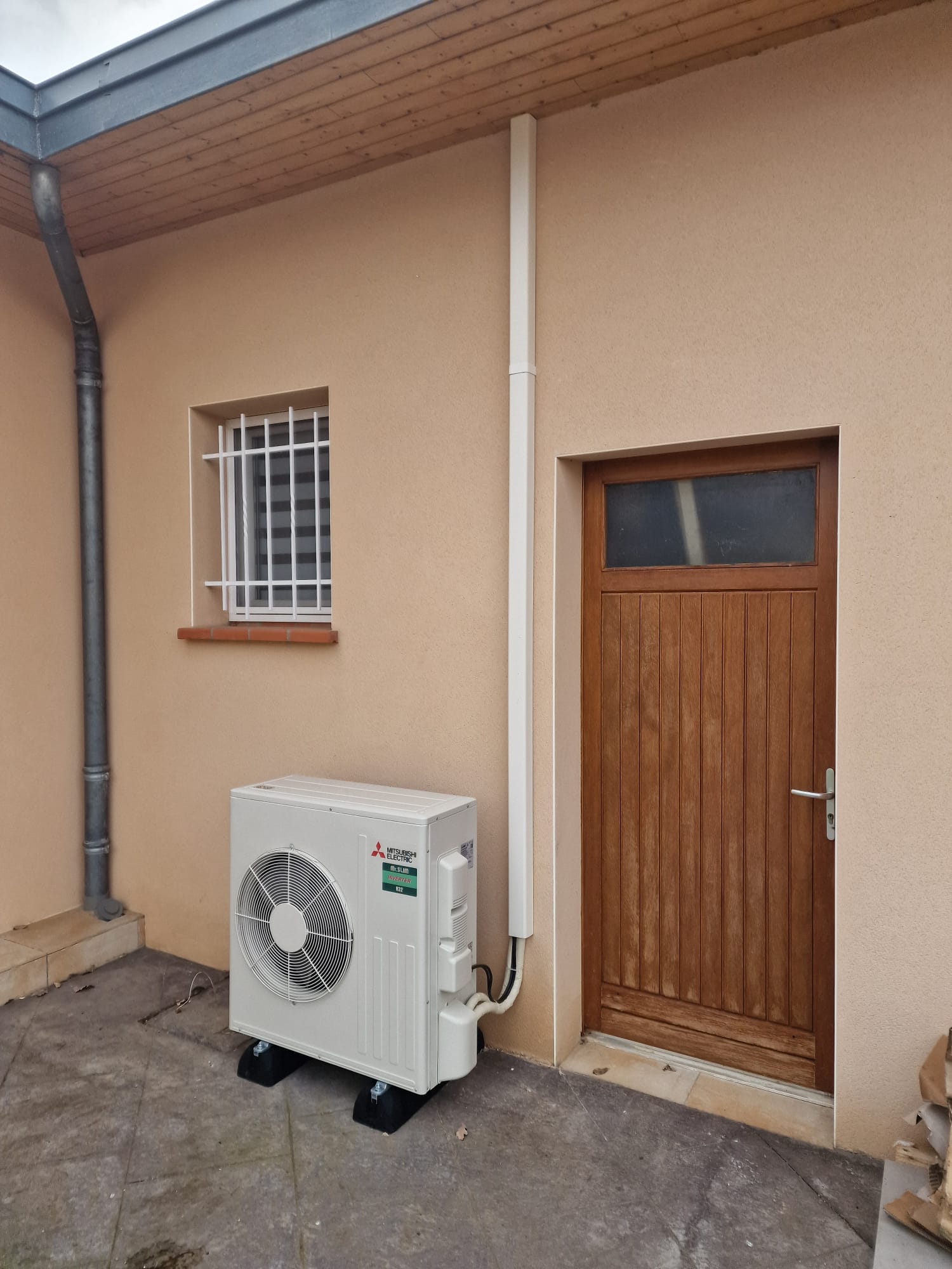 Unité extérieure de pompe à chaleur installée au sol contre une maison