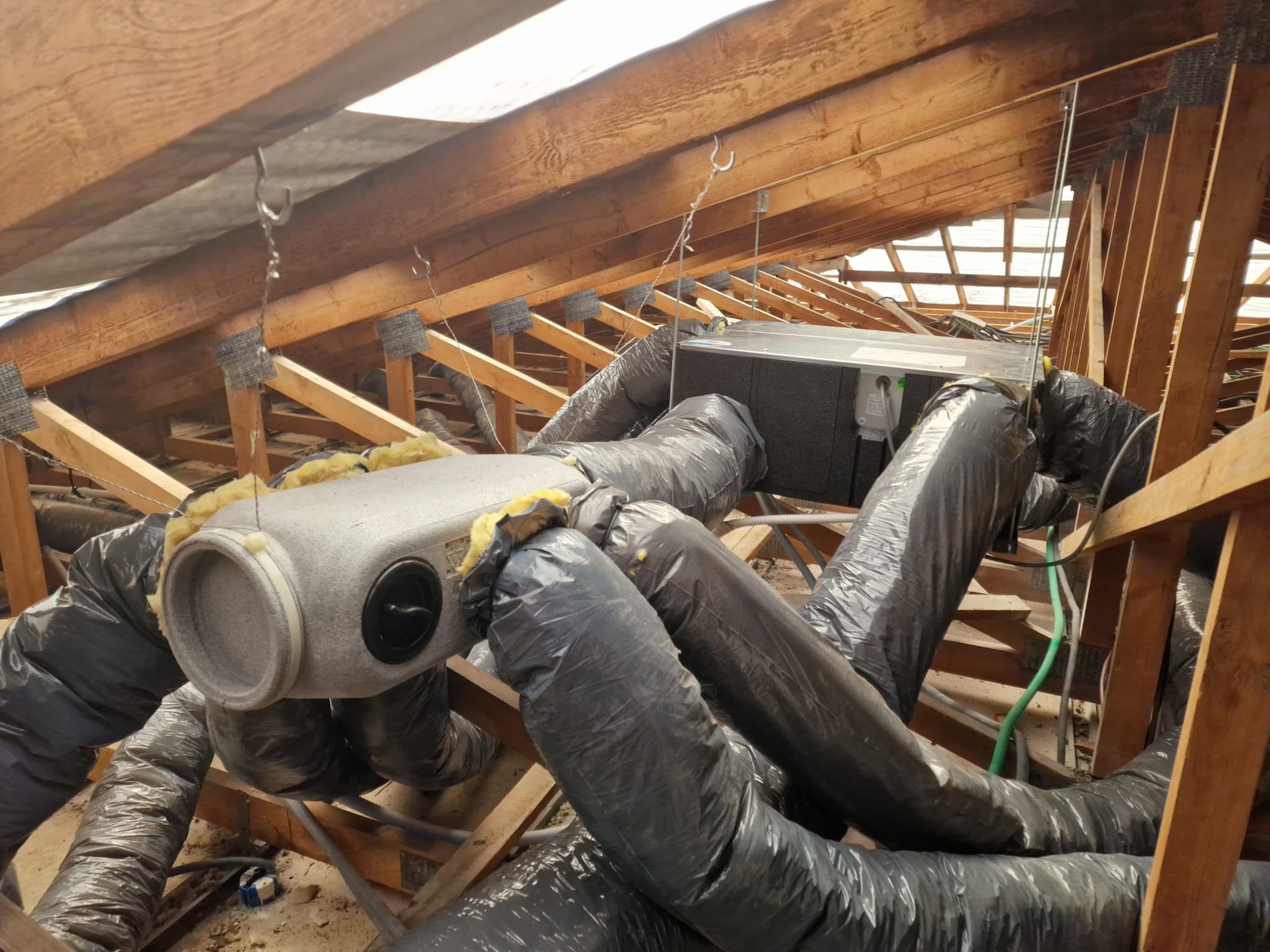 Réseau de gaines de VMC et caisson de distribution installés dans des combles